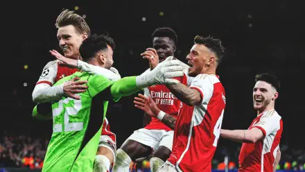 Sports soccer HD PC desktop wallpaper showing Arsenal F.C. players in red-and-white kits and a green goalkeeper celebrating a goal together under stadium lights.