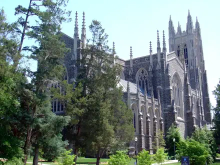 Duke University Gothic building with soaring spires and arched windows framed by trees, presented as a 2K Quad HD PC desktop wallpaper and background.