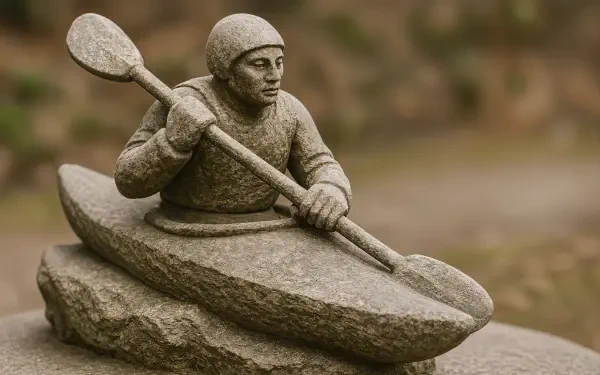 Stone sculpture of a kayaker paddling a carved kayak against a softly blurred natural background — 4K Ultra HD PC desktop wallpaper and background.