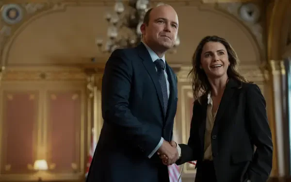 Two actors from the TV show The Diplomat shake hands in an ornate room; 2K Quad HD PC desktop wallpaper/background with formal attire and warm, elegant lighting.