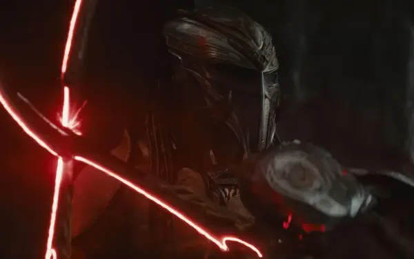 Dark close-up of the Predator from the movie Predator: Badlands, a red targeting laser slicing across its armored helmet — 4K Ultra HD PC desktop wallpaper and background.