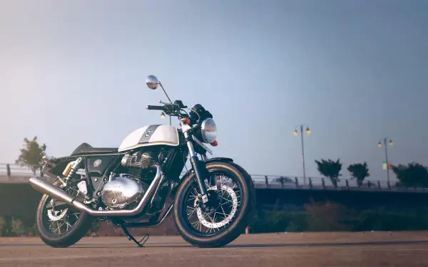 Side view of a Royal Enfield Continental GT 650 motorcycle parked on a waterfront promenade, HD PC desktop wallpaper background.