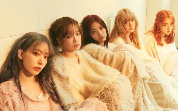 Five women in soft cream outfits seated against a pale wall in warm golden light — serene group portrait, 4K Ultra HD PC desktop wallpaper and background.