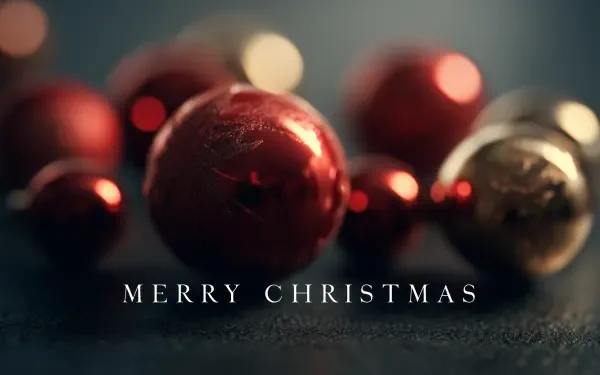 Close-up of red and gold Christmas ornaments and balls with Merry Christmas text, 2K Quad HD PC desktop wallpaper and background.