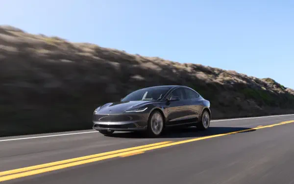 Sleek Tesla Model 3 electric car cruising on a sunlit highway, presented as a 4K Ultra HD PC desktop wallpaper background.