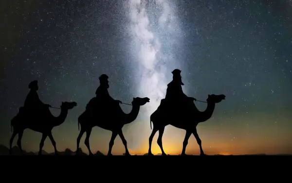 Silhouetted Biblical Magi on camels crossing a desert beneath a brilliant starry sky and Milky Way — HD PC desktop wallpaper/background.
