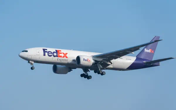 FedEx delivery airplane in flight against a clear blue sky, 5K Ultra HD PC desktop wallpaper background.