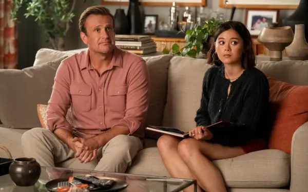 4K Ultra HD desktop wallpaper — TV show Shrinking still: a man and woman sit on a living-room couch with surprised expressions, notebook on her lap and a coffee table in the foreground.