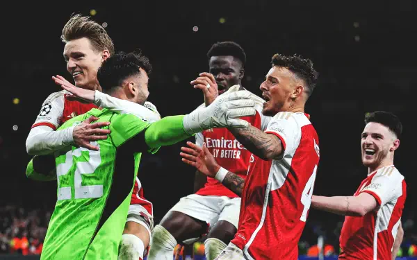 Sports soccer HD PC desktop wallpaper showing Arsenal F.C. players in red-and-white kits and a green goalkeeper celebrating a goal together under stadium lights.