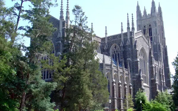 Duke University Gothic building with soaring spires and arched windows framed by trees, presented as a 2K Quad HD PC desktop wallpaper and background.