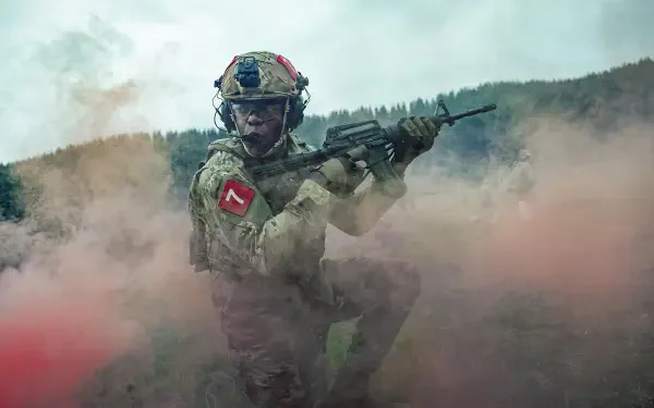 5K Ultra HD PC desktop wallpaper for the movie War Machine (2026): a helmeted soldier aims a rifle through swirling colored battlefield smoke.