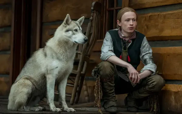 Outlander TV scene: a young man seated beside a Siberian husky in a rustic cabin, 5K Ultra HD PC desktop wallpaper.