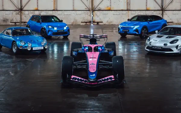 4K Ultra HD desktop wallpaper: Alpine F1 Team pink-and-blue Formula 1 car front and center, flanked by blue and white Alpine road cars in a reflective hangar.