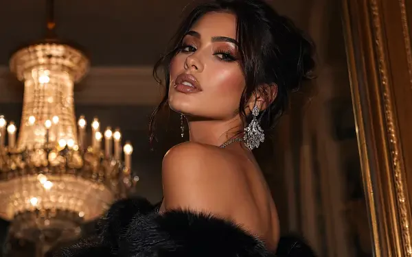 Glam woman in evening gown and fur, jeweled earrings, looking over her shoulder before a crystal chandelier — 4K Ultra HD PC desktop wallpaper and background.