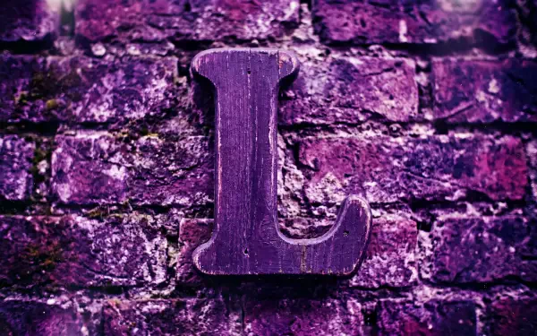 5K Ultra HD PC desktop wallpaper of the letter L (alphabet): carved wooden L mounted on a textured purple brick wall.