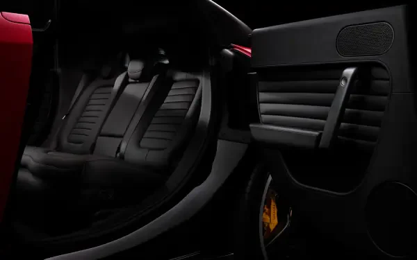 Ferrari Luce interior close-up: black leather seats, sculpted door panel and red exterior trim, 4K Ultra HD PC desktop wallpaper background.