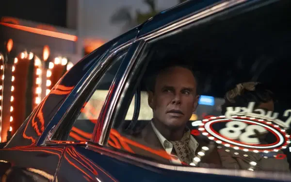 HD PC desktop wallpaper/background from Fallout (TV Show): a tense man in a suit sits inside a retro car, neon casino lights reflected on the window.