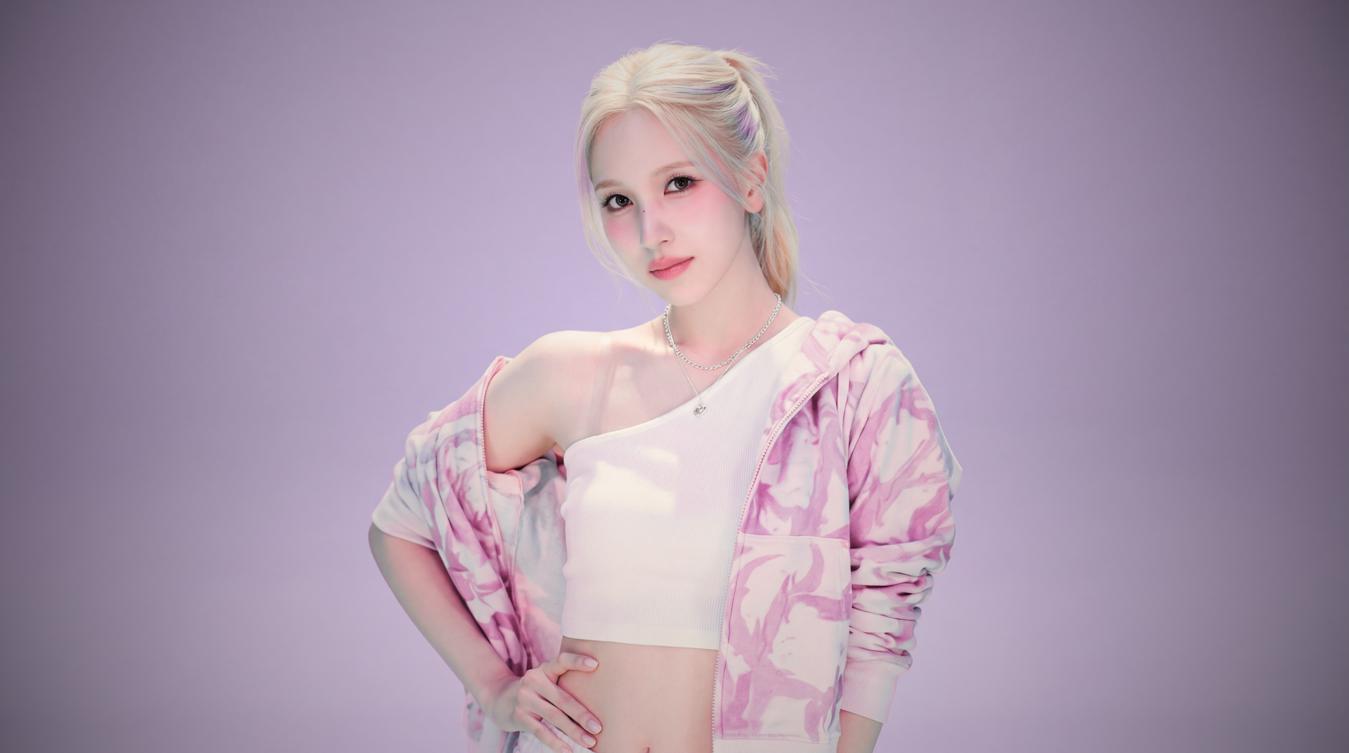 5K desktop wallpaper of a blonde K-pop–style singer/model in a white crop top and pastel pink jacket, posing confidently against a soft lavender background.