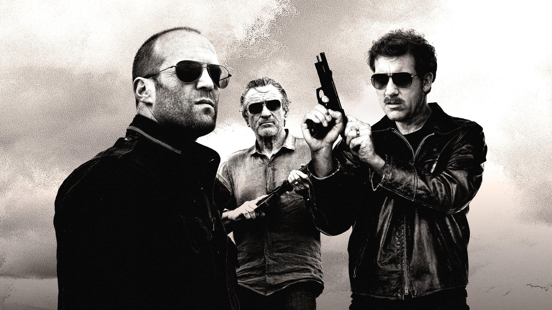 Killer Elite 4K Ultra HD PC desktop wallpaper: gritty black-and-white shot of three armed men in sunglasses and leather jackets against a stormy sky.