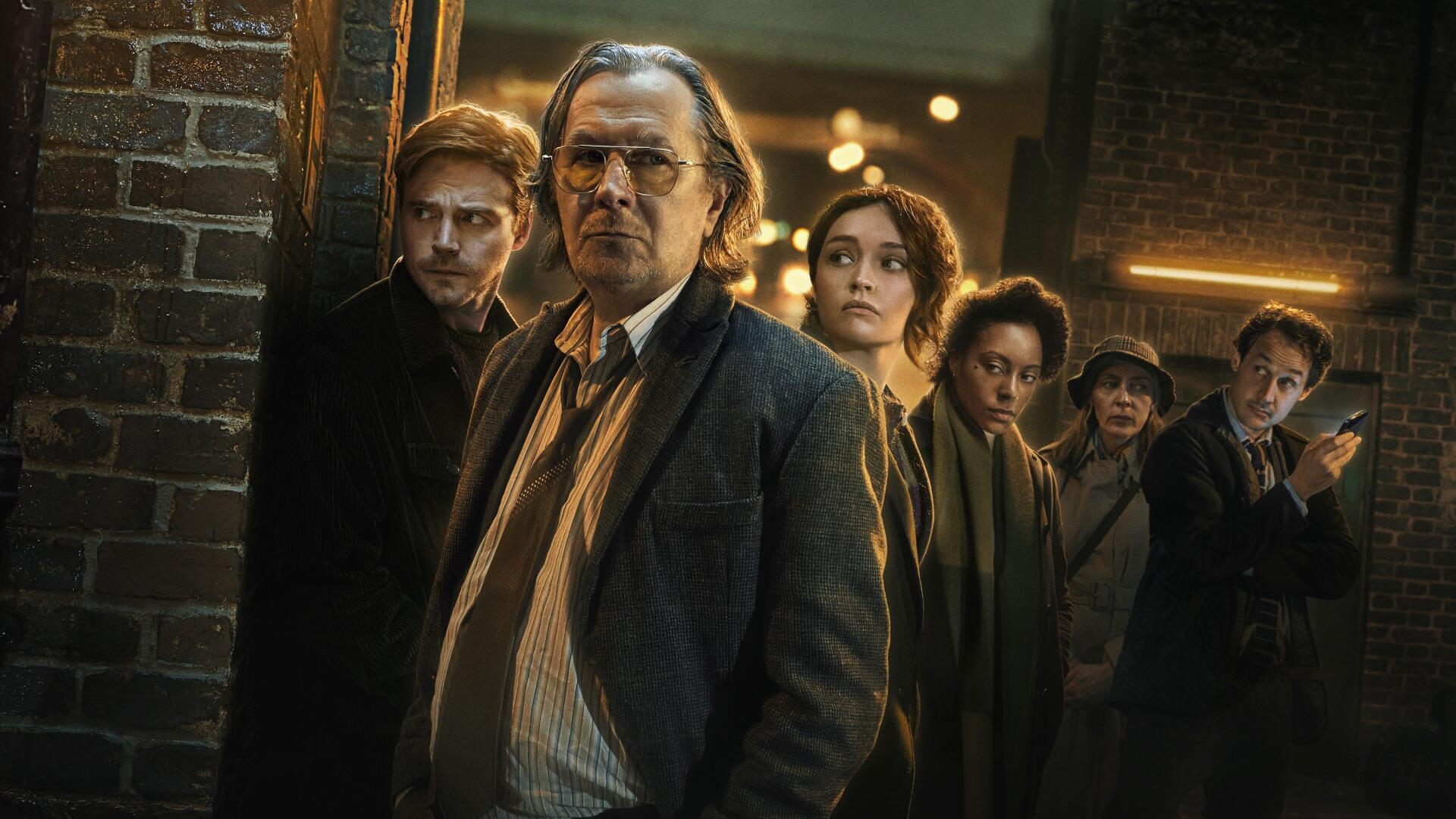 Slow Horses 4K Ultra HD PC desktop wallpaper: gritty night-alley scene of a ragged team of intelligence operatives led by a stern older man, moody lighting and brick urban backdrop.