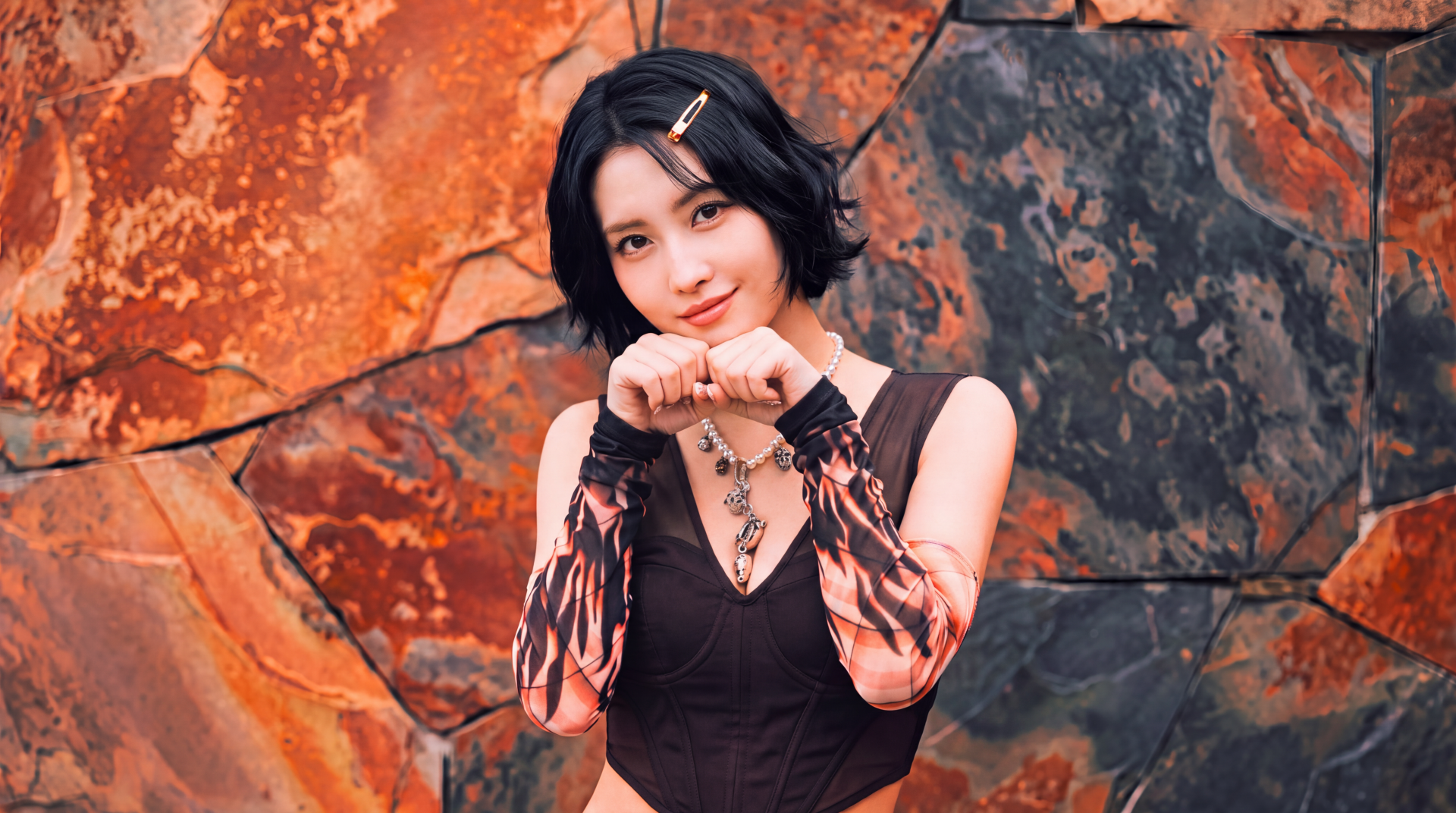 5K Ultra HD desktop wallpaper: short-haired Japanese model posing with hands near her face against a rusted stone backdrop, styled in a K-pop idol TWICE/MiSaMo aesthetic.
