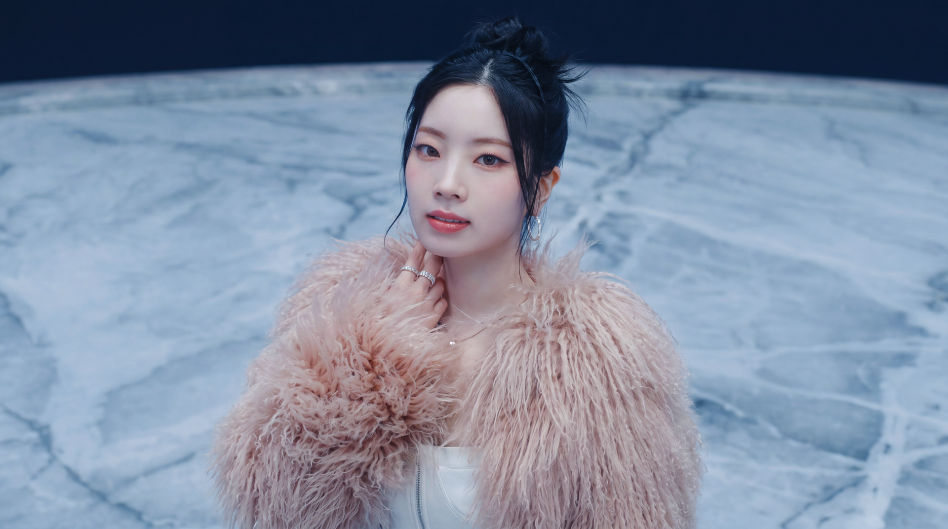 5K desktop wallpaper: portrait of a Korean K-pop idol and model in a fluffy pink fur coat, dark updo, poised against a cool marble-blue background.