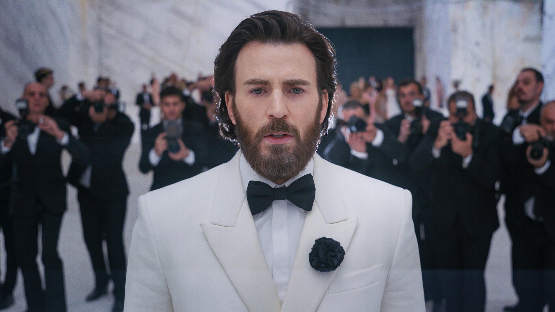 Chris Evans in a white tuxedo and beard at a formal event in Sacrifice (2026), HD PC desktop wallpaper background.