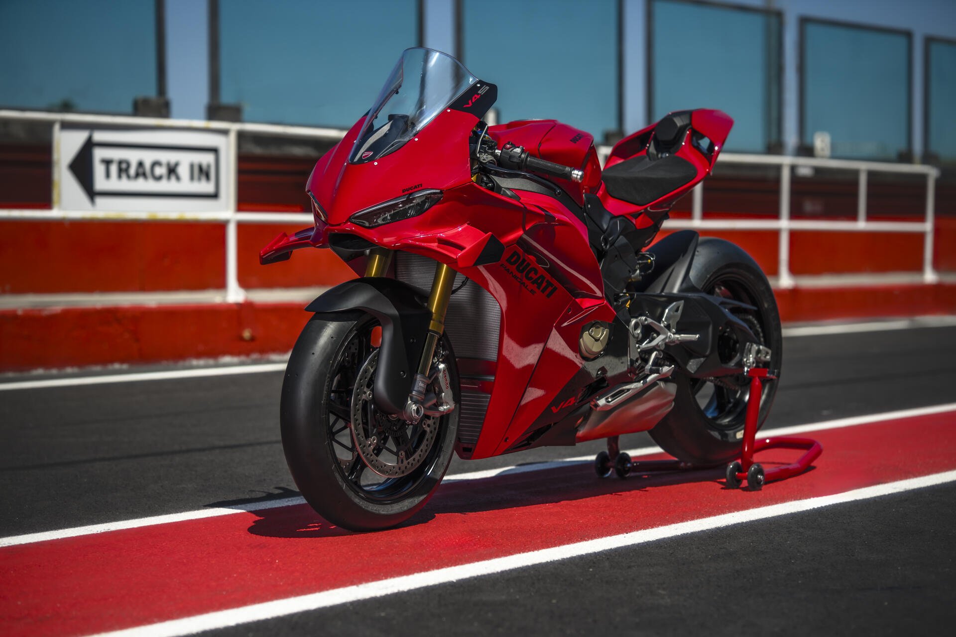 Red Ducati Panigale V4 sport bike on a racetrack, featured in an 8K Ultra HD PC desktop wallpaper and background.