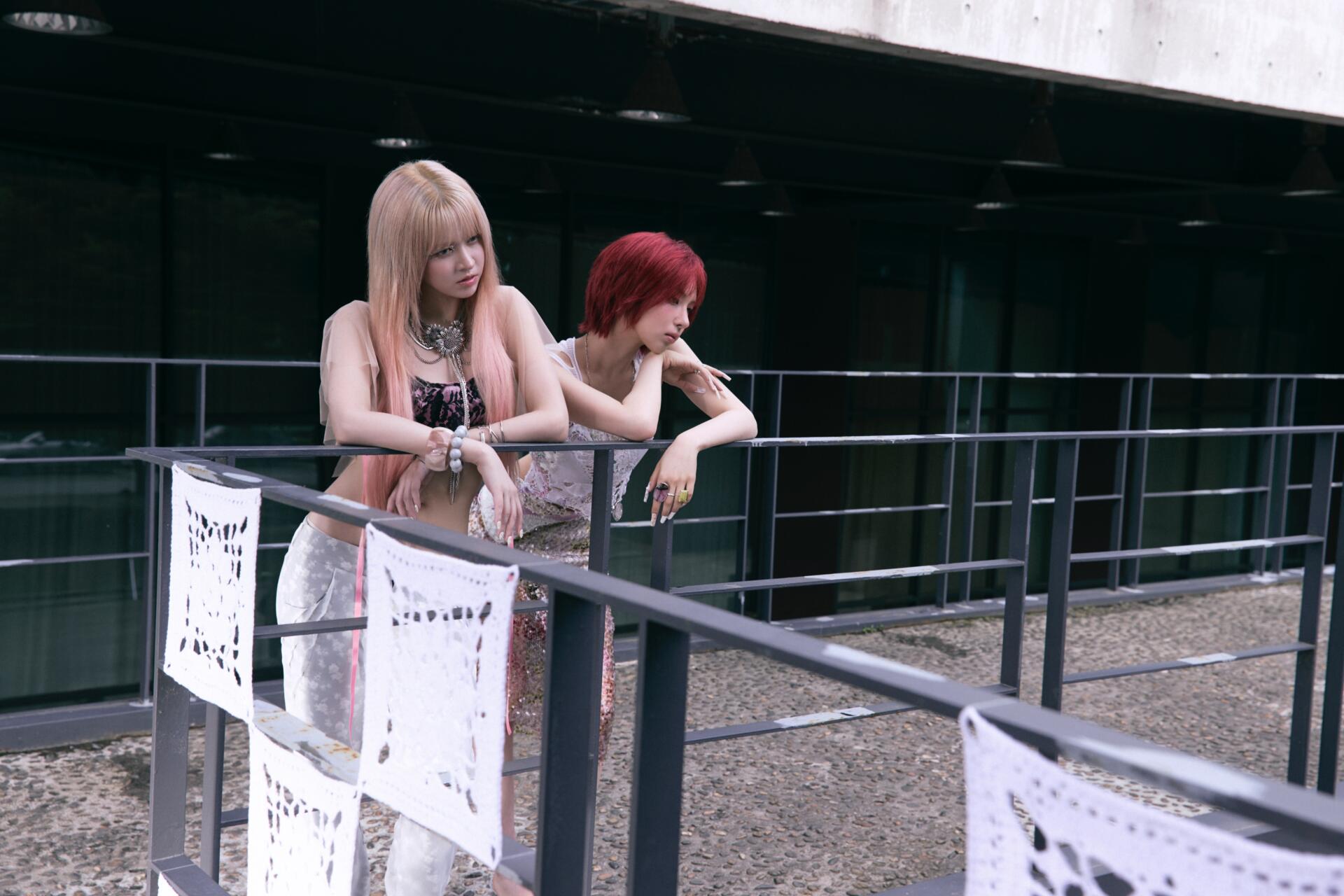 NMIXX Strange Muse 4K Ultra HD desktop wallpaper featuring two women leaning over a metal railing.