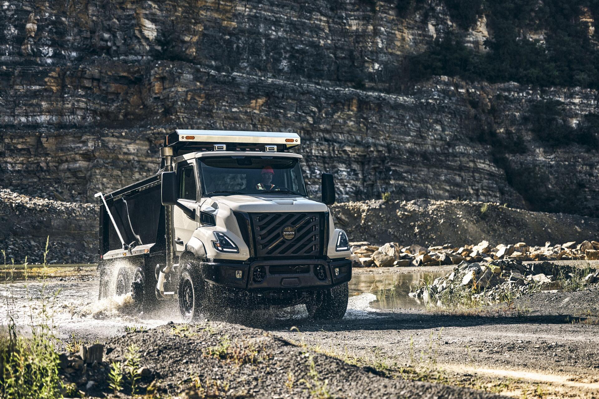 Volvo VNX off-road truck splashing through a rocky stream, shown in a 5K Ultra HD PC desktop wallpaper.