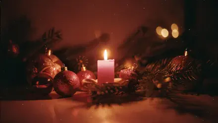 Warm glowing Christmas candle amid evergreen branches and red baubles with soft bokeh — 4K Ultra HD PC desktop wallpaper background.