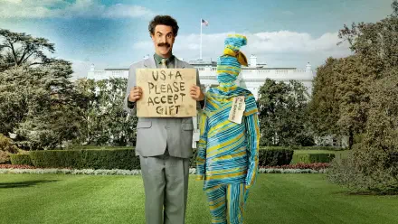 Borat 2 4K Ultra HD PC desktop wallpaper: man in gray suit holds USA please accept gift cardboard sign beside a person wrapped in striped cloth on the White House lawn.