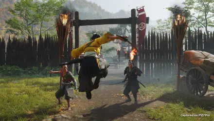 HD PC desktop wallpaper/background from Ghost of Yōtei: a samurai in yellow leaps through a gate, sword raised amid torches and a wooden palisade during a fierce battle.