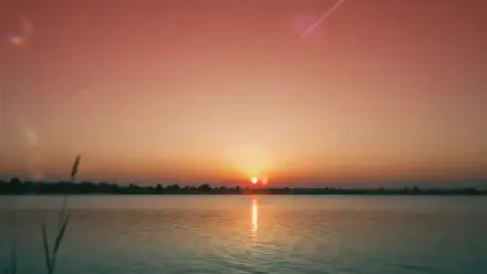2K Quad HD PC desktop wallpaper and background: summer sunset over calm water, orange-pink sky with the sun low on the horizon and its reflection rippling on the lake.
