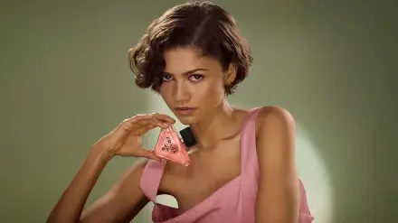Close-up of a female celebrity in a pink dress holding a triangular perfume bottle against a soft green backdrop — 4K Ultra HD PC desktop wallpaper and background.