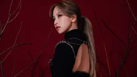 5K desktop wallpaper: side profile of a Japanese model and singer in K-pop–inspired styling, black open-back outfit and ponytail against a deep red background.