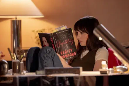 Dakota Johnson reads Verity in a warmly lit room, featured in a 4K Ultra HD PC desktop wallpaper and background for Verity (2026).