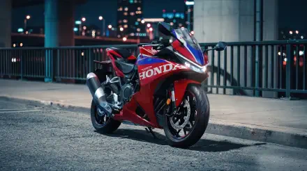 Red Honda CBR500R sport bike parked on a city street at night, featured in a 5K Ultra HD desktop wallpaper.