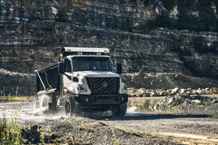 Volvo VNX off-road truck splashing through a rocky stream, shown in a 5K Ultra HD PC desktop wallpaper.