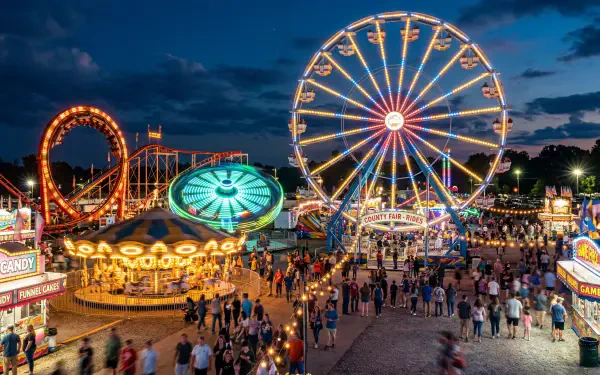 Nighttime fair with illuminated Ferris wheel, carousel and bustling midway — 5K Ultra HD PC Desktop Wallpaper and Background.