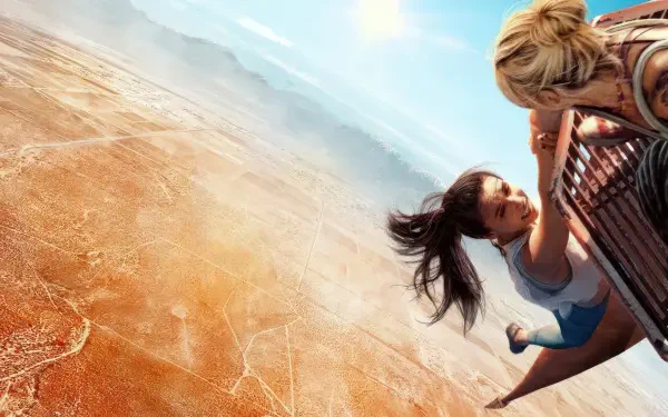 Vertigo 4K Ultra HD PC desktop wallpaper: two figures clutch a railing, hanging over a dizzying desert abyss with a sweeping sky and dramatic downward perspective.