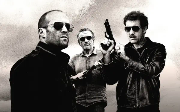 Killer Elite 4K Ultra HD PC desktop wallpaper: gritty black-and-white shot of three armed men in sunglasses and leather jackets against a stormy sky.