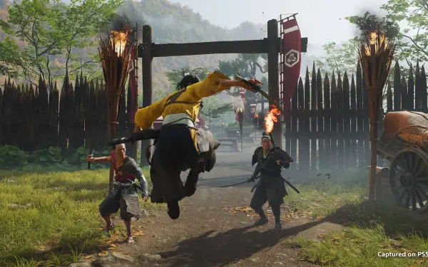 HD PC desktop wallpaper/background from Ghost of Yōtei: a samurai in yellow leaps through a gate, sword raised amid torches and a wooden palisade during a fierce battle.