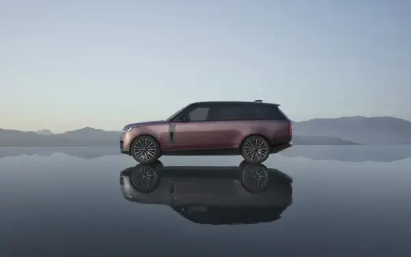 Range Rover Electric SUV in profile reflected on a mirror-like surface with distant mountains — 8K Ultra HD PC desktop wallpaper/background.
