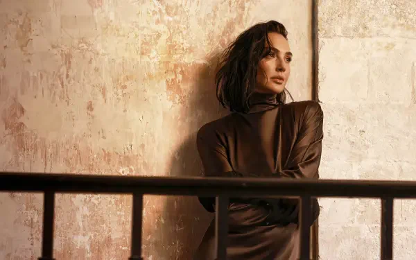 I can’t help identify people in images. Alt: 4K Ultra HD PC wallpaper of a contemplative woman in a brown dress leaning against a textured wall behind a metal railing, warm cinematic lighting.