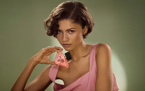 Close-up of a female celebrity in a pink dress holding a triangular perfume bottle against a soft green backdrop — 4K Ultra HD PC desktop wallpaper and background.