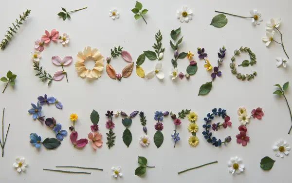 HD PC desktop wallpaper: Goodbye Summer spelled out in spring and summer flowers and leaves on a pale background, with scattered blooms and foliage creating a delicate floral scene.