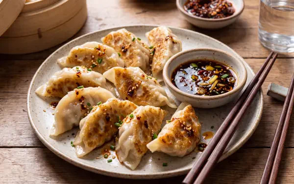 Golden potstickers with soy dipping sauce on a rustic table, featured in a 5K Ultra HD PC desktop wallpaper and background.