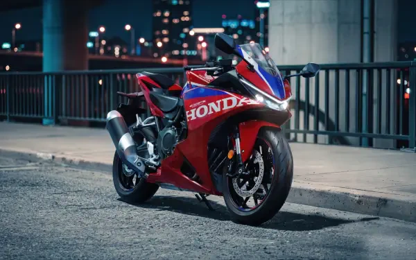 Red Honda CBR500R sport bike parked on a city street at night, featured in a 5K Ultra HD desktop wallpaper.