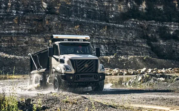 Volvo VNX off-road truck splashing through a rocky stream, shown in a 5K Ultra HD PC desktop wallpaper.